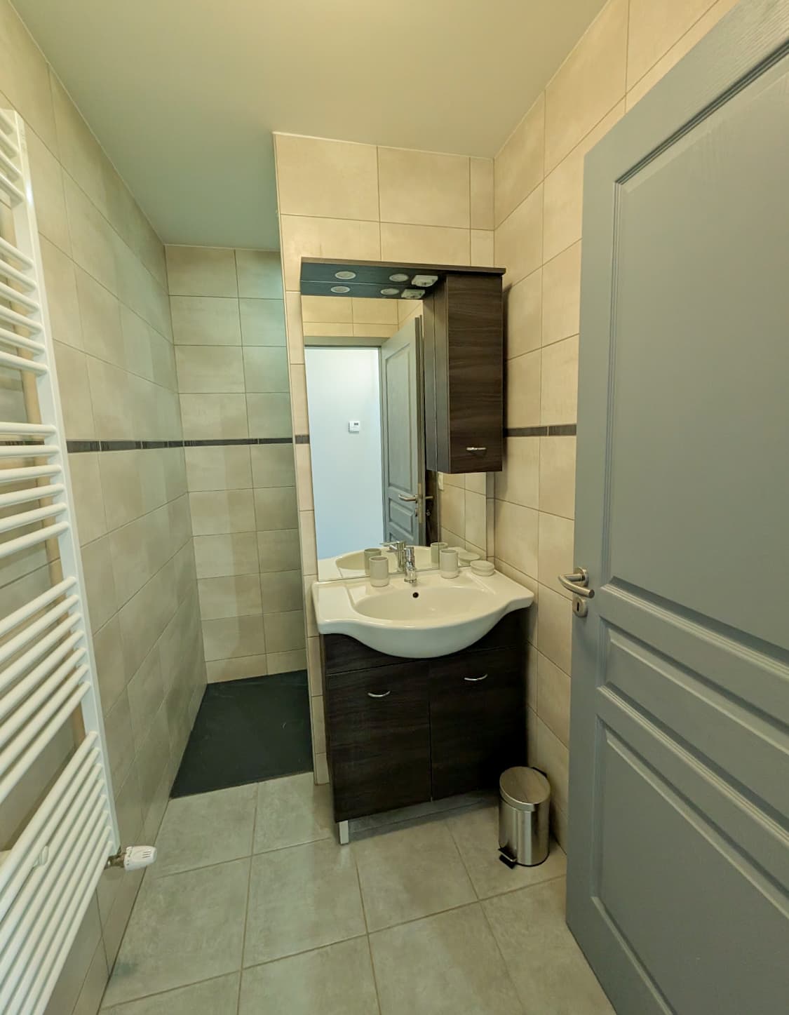 Salle d’eau avec vasque, rangements et sèche-serviettes